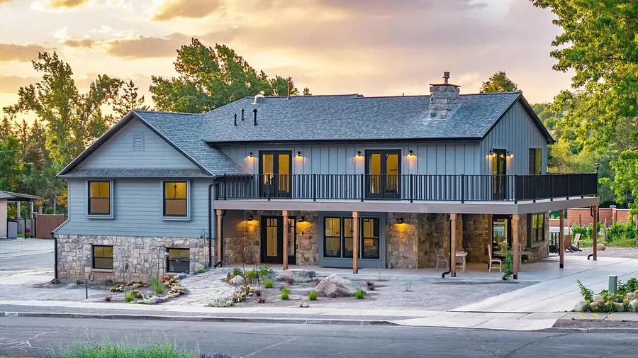 Little Gem gray board-and-batten exterior with stone base and upper balcony at sunset