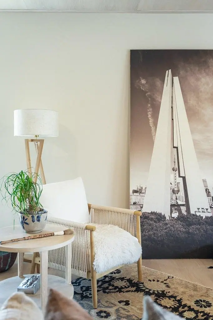 Reading corner with rope-frame lounge chair, round wood tables, linen lamp, and large architectural artwork