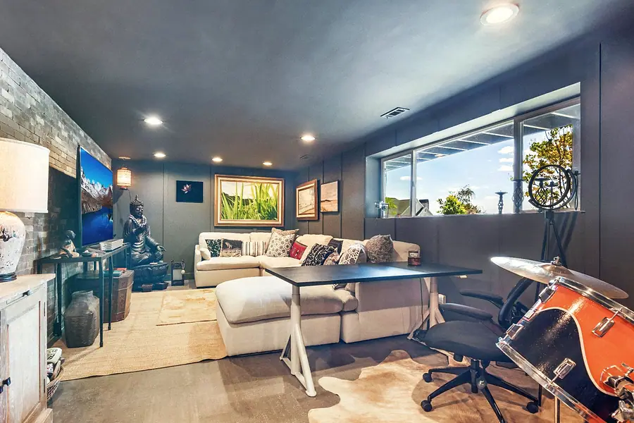 Wallace Project basement lounge with sectional sofa, desk, drum kit, and clerestory windows