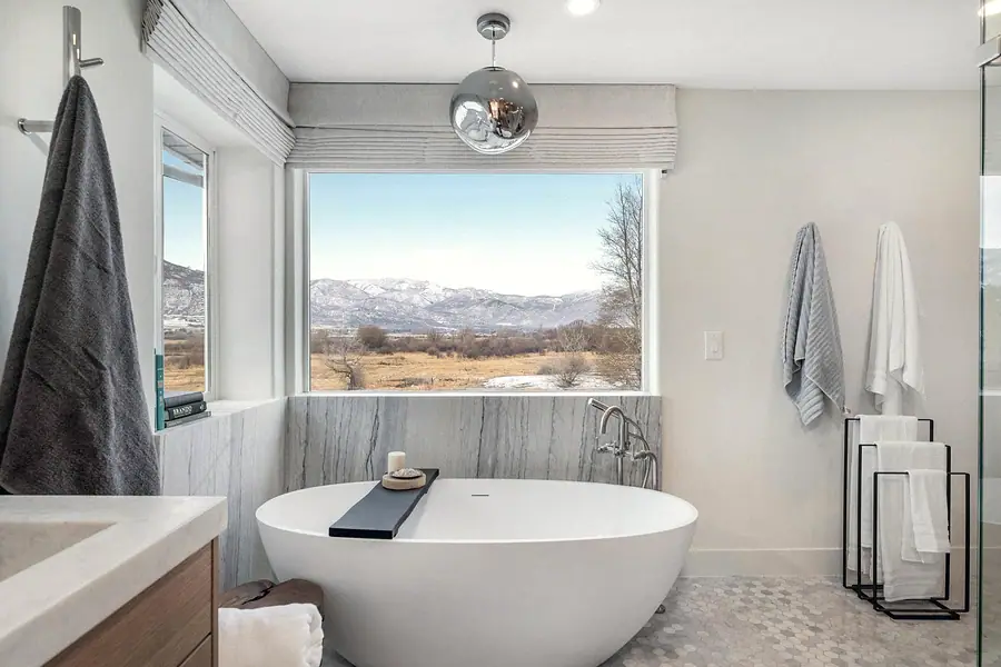 Primary bath freestanding tub with marble surround and mountain picture window