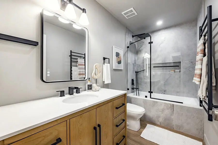 6468 S Brookstone bathroom with oak vanity, lit mirror, and glass tub shower
