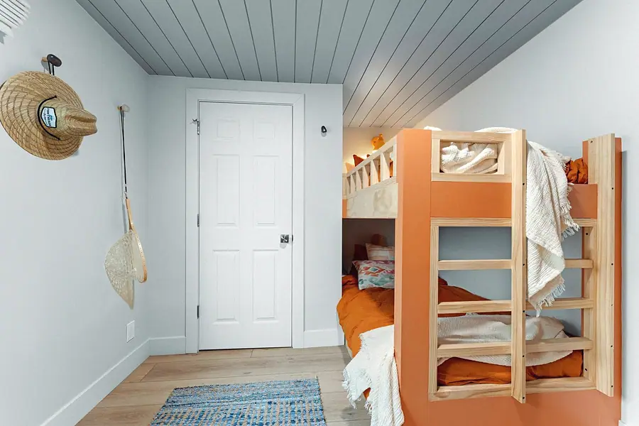 Midway orange bunk beds with wood ladder, fishing hat, and net on the wall