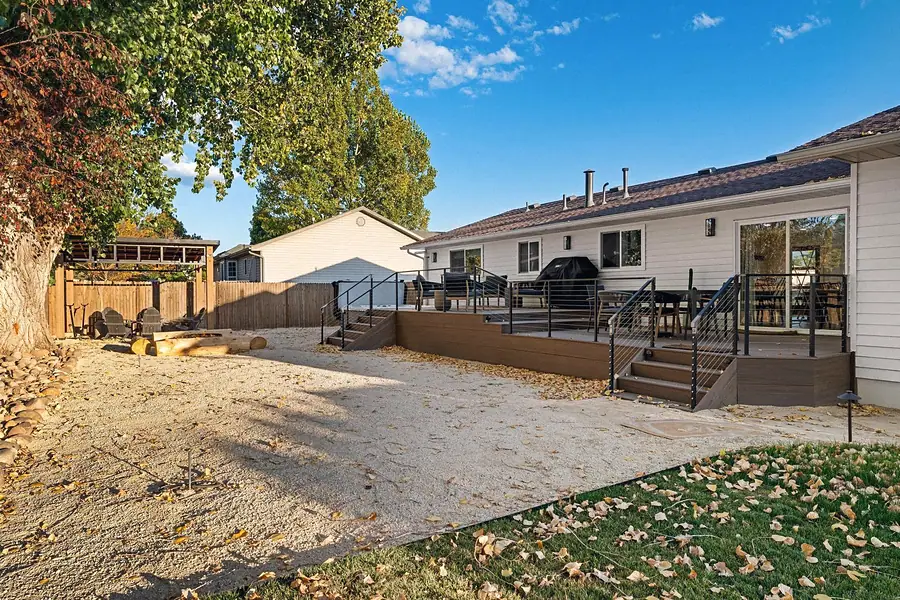 Midway raised composite deck with cable rail stairs overlooking gravel yard and fire pit