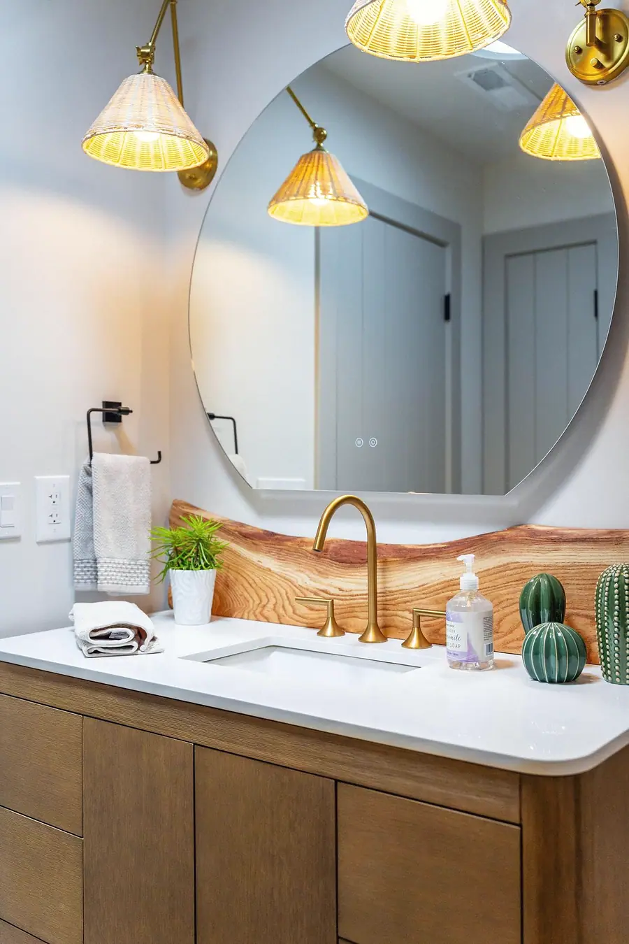Little Gem powder vanity with live-edge wood backsplash, brass faucet, and woven sconces