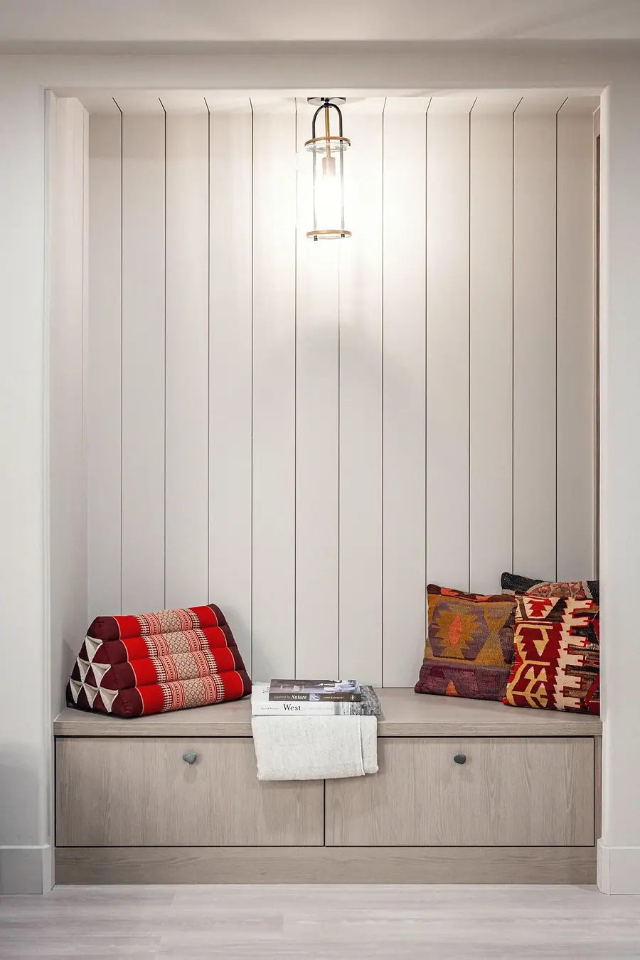 Grand Vista built-in reading nook with vertical paneling, pendant light, and kilim pillows