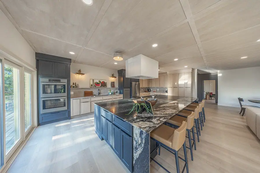Landmark kitchen island in dark stone with leather stools and double wall ovens
