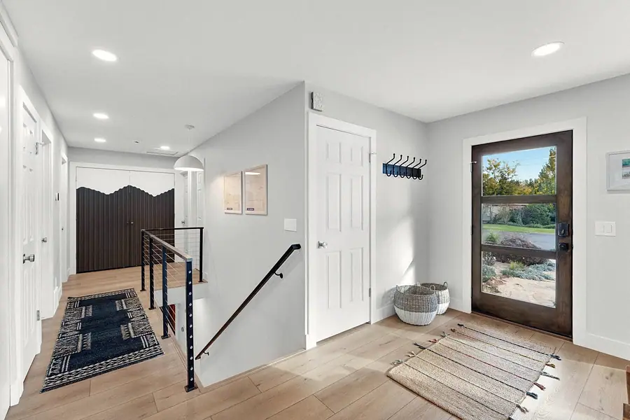Midway upper hall entry with glass front door, cable stair rail, and mountain-motif closet doors
