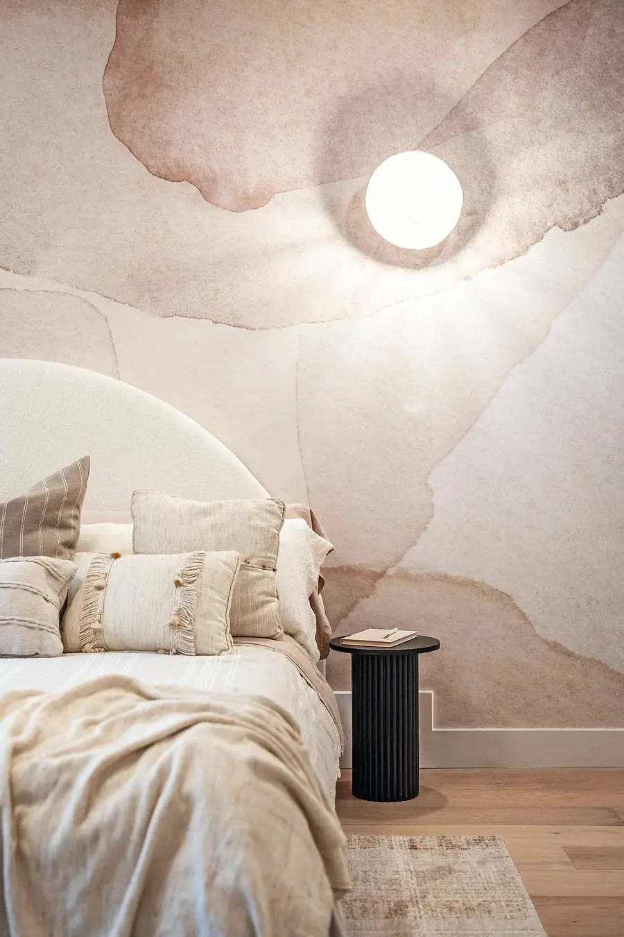 Grand Vista bedside detail with fluted black nightstand, globe sconce, and mural wall