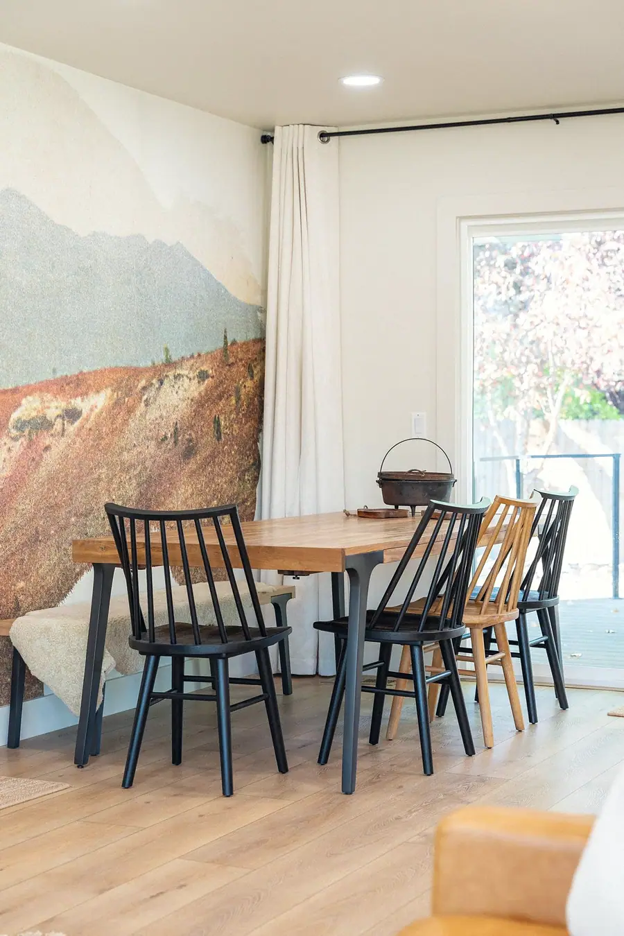 Midway dining area with wood table, black and natural spindle chairs, and patio doors