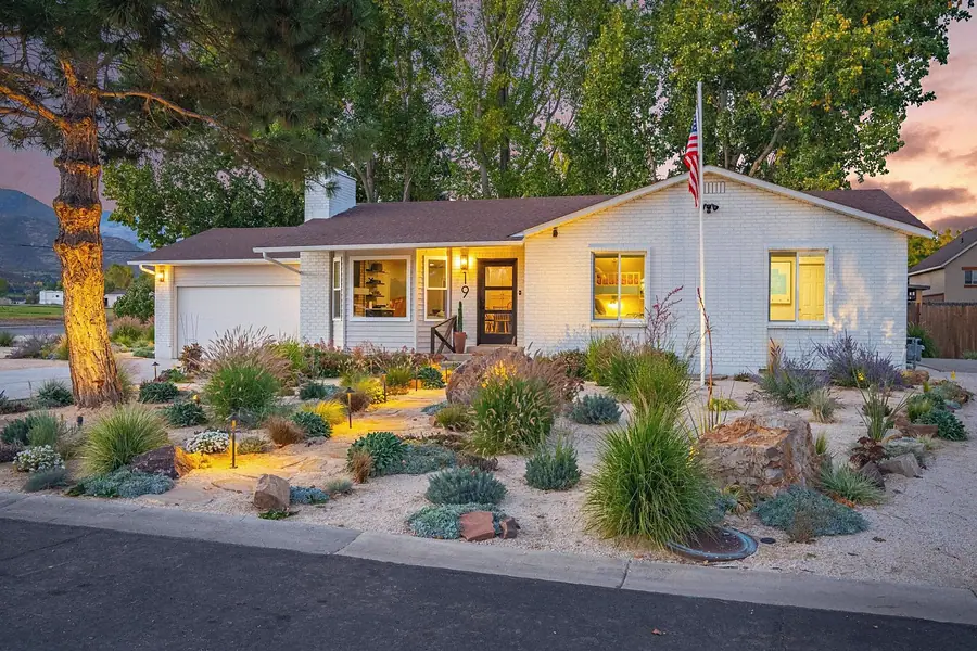 Midway vacation home exterior at sunset with mountain backdrop and lit path lights