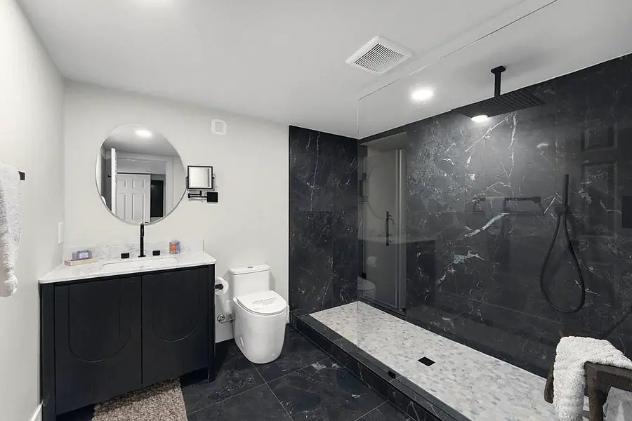 Crista da Montanha bath with black vanity, round mirror, and dark marble walk-in shower