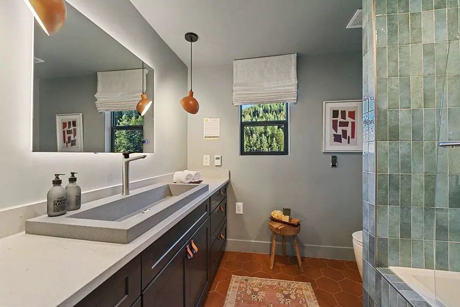 Matterhorn Hygge House bath with concrete trough sink, terracotta floor, and green tile shower