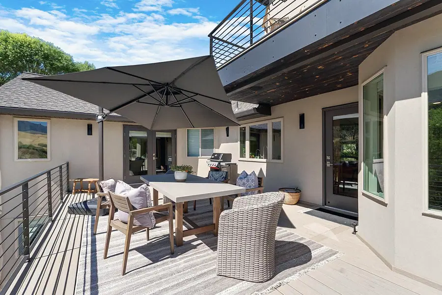 Elysium covered deck dining with umbrella, grill, and mountain backdrop