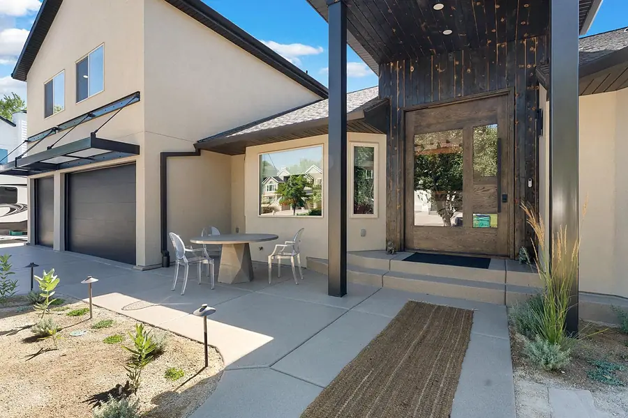 Elysium entry courtyard with glass-panel wood doors and outdoor dining table