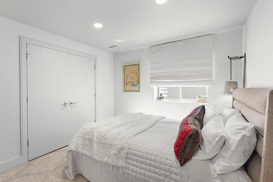 Elysium guest bedroom with white bedding, closet doors, and rope sconce