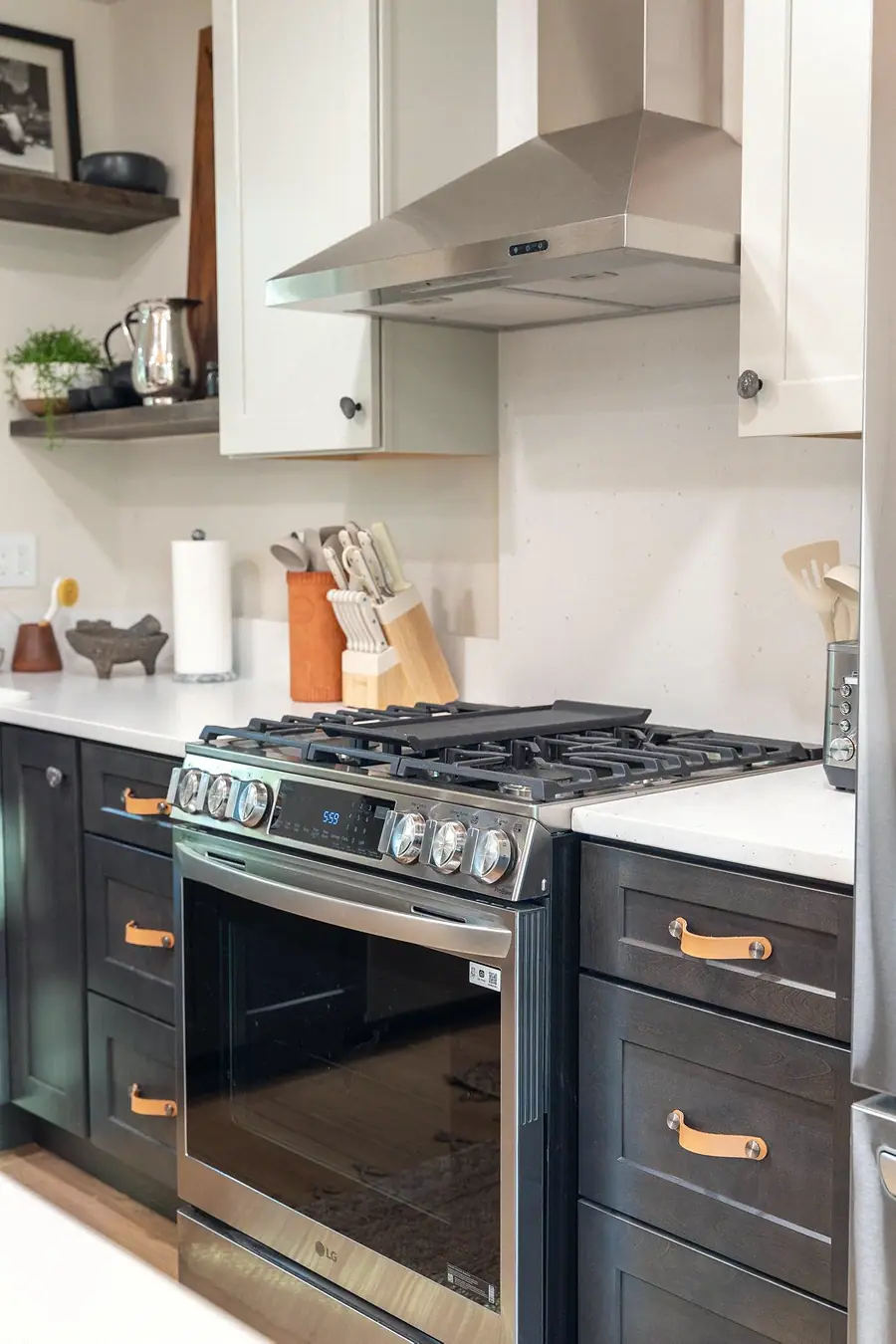 Midway kitchen range with stainless hood, dark cabinetry, and warm wood accents