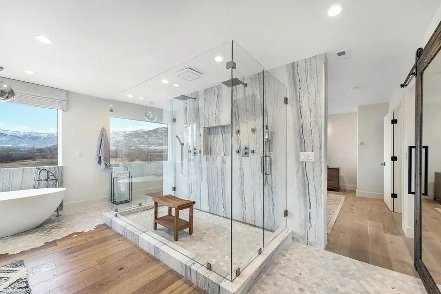 Marble walk-in shower with glass enclosure opening to the spa bath