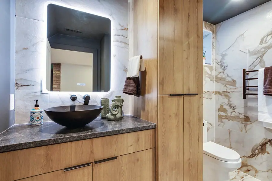 Wallace Project bathroom with vessel sink, lit mirror, and light wood cabinetry