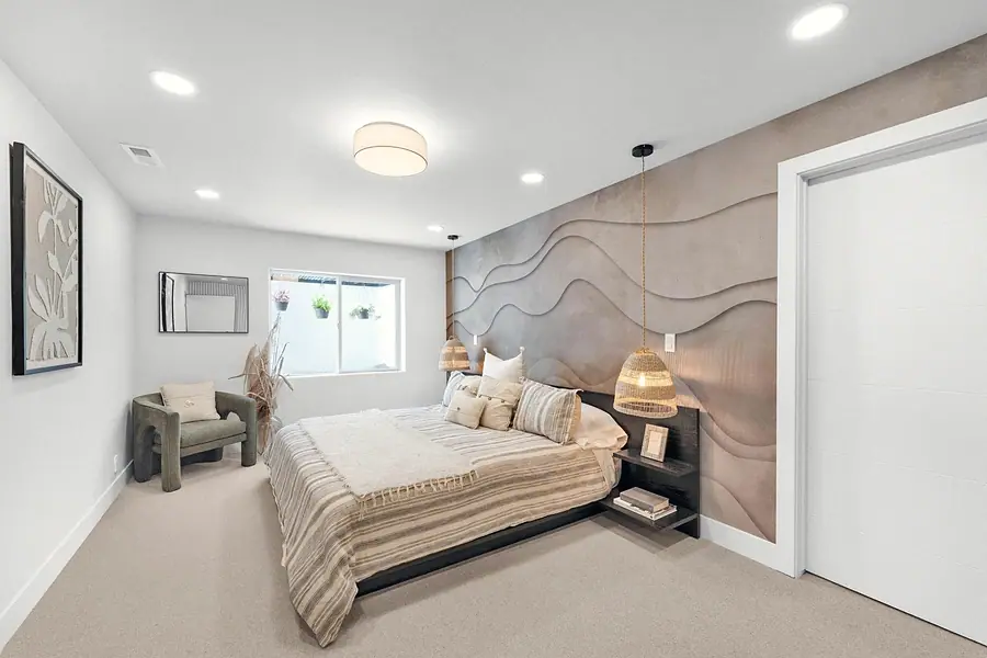 Grand Vista bedroom with sculpted wave feature wall, woven pendant lights, and striped bedding