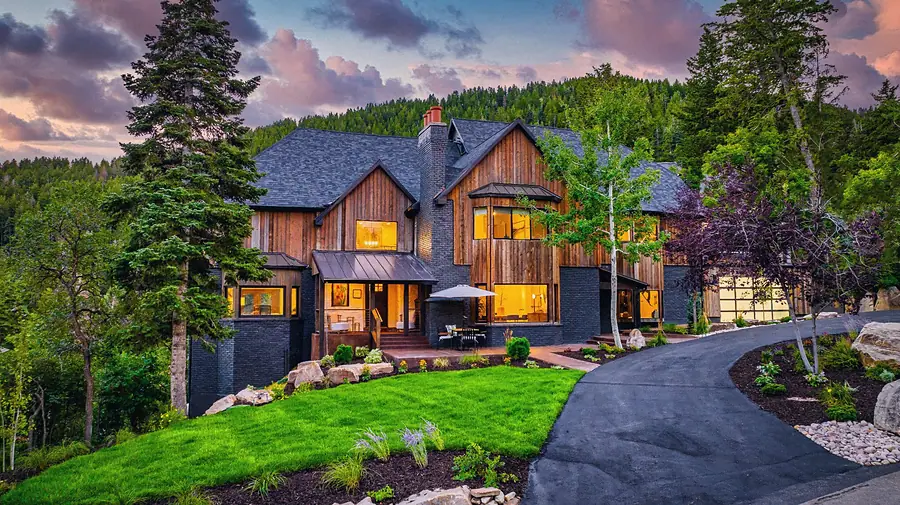 Matterhorn Hygge House front elevation at sunset with lawn, driveway, and forest backdrop