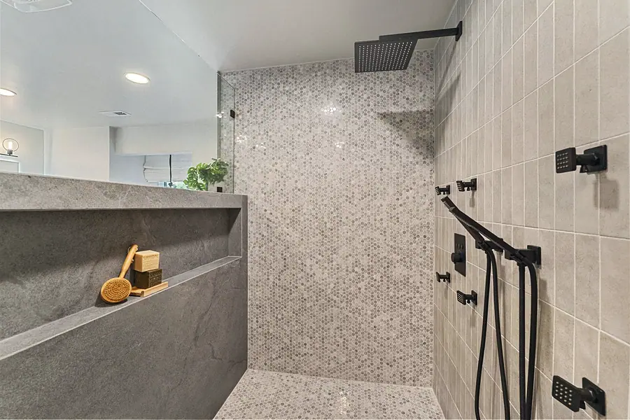 Matterhorn Hygge House walk-in shower with pebble mosaic wall and matte black fixtures