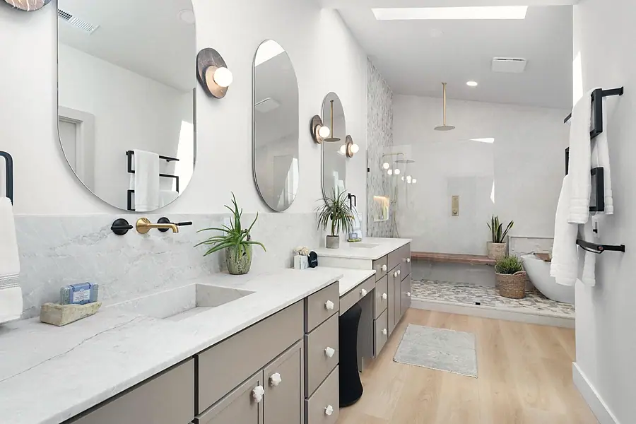 Little Gem primary bath with marble double vanity, oval mirrors, and walk-in shower beyond