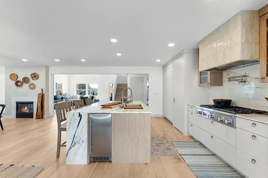 Grand Vista open kitchen with marble island, range wall, and fireplace beyond