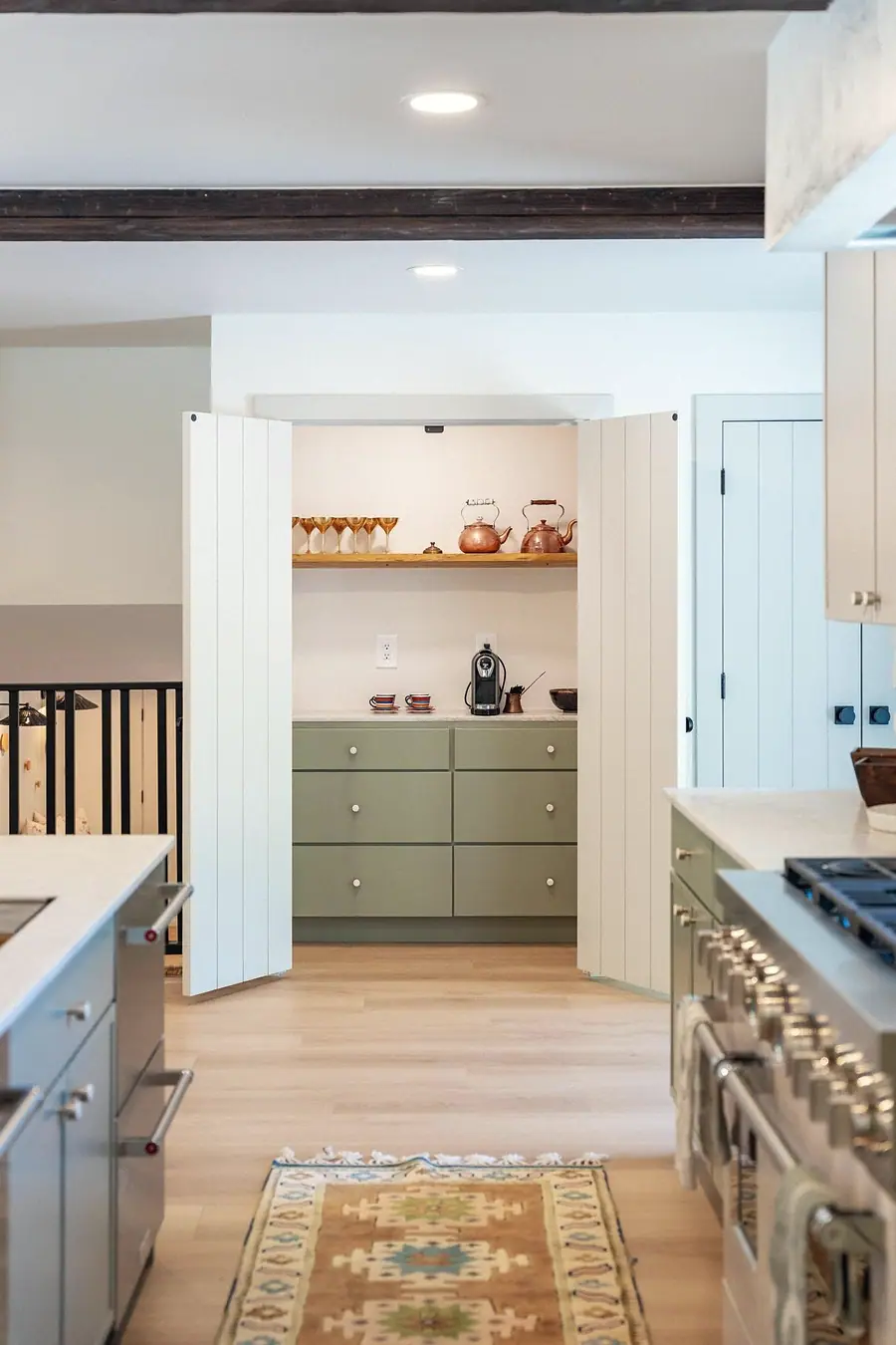 Little Gem pantry with sage drawers, copper kettles, and open bifold doors