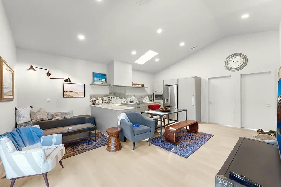 Elysium living room with sofa, striped chair, kitchen island, and dining beyond
