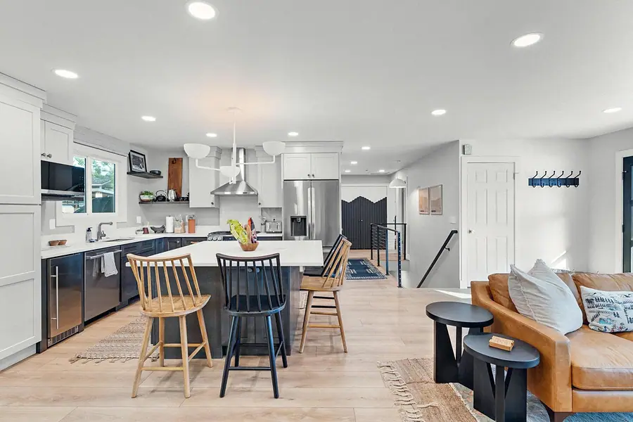 Midway open kitchen and living area with white cabinetry, island seating, and leather sofa