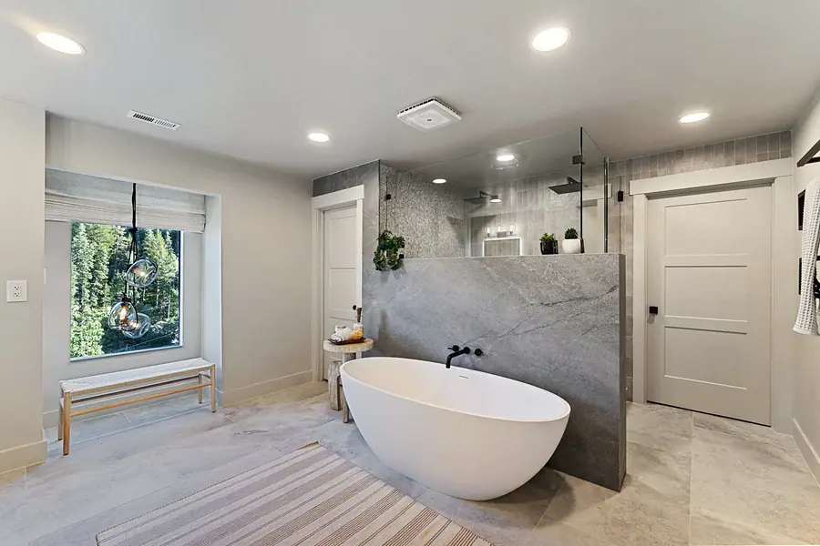 Matterhorn Hygge House spa bath with freestanding tub, glass shower, and forest window