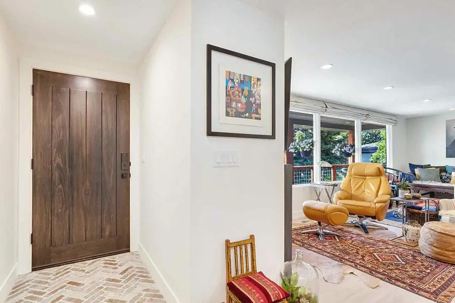 Wallace Project entry with wood door looking into living room with mustard lounge chair
