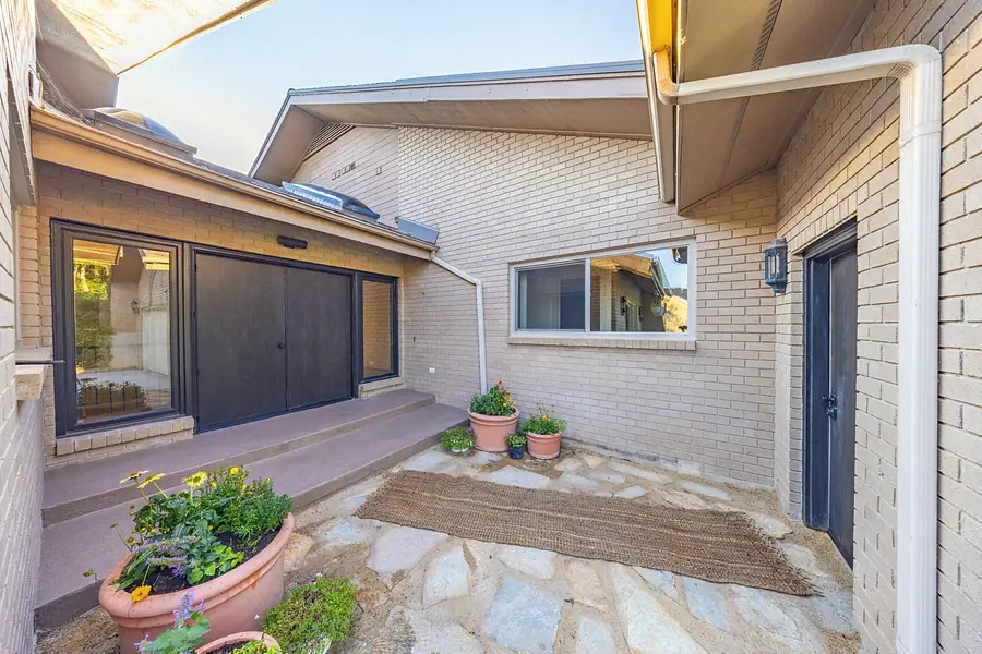 Redesigned stone courtyard entry with potted plants and dark double doors