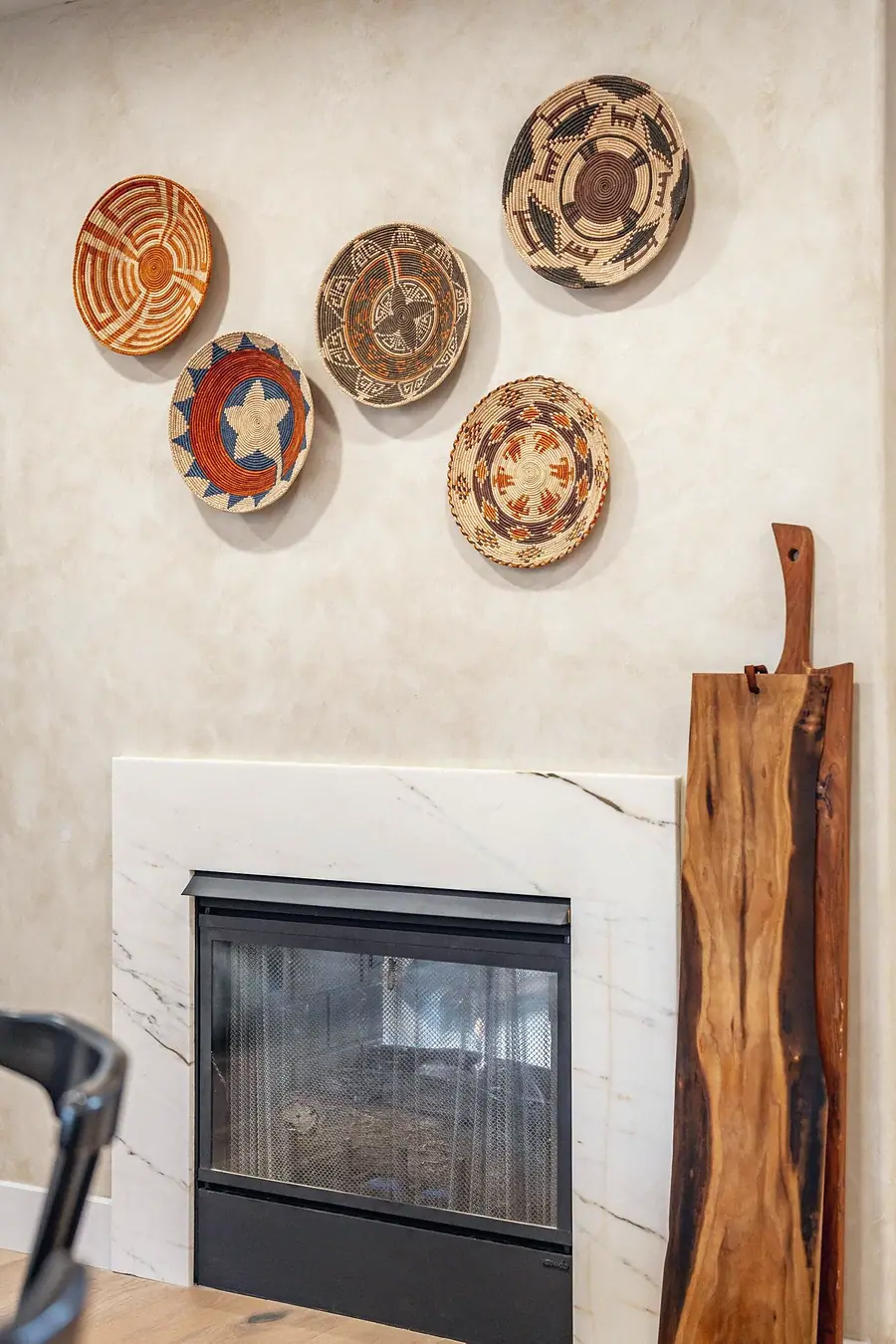 Grand Vista fireplace with marble surround, woven wall baskets, and wood cutting boards