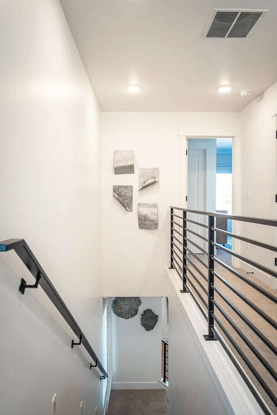 Silver Creek upper stair landing with metal rail and textured wall art