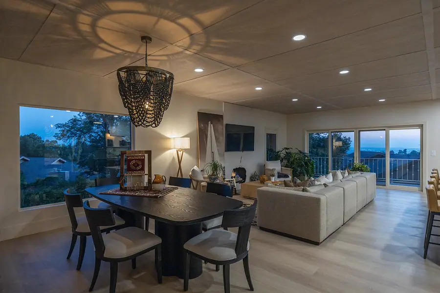 Lower-level kitchen bar with light wood island, dining area, and patio doors