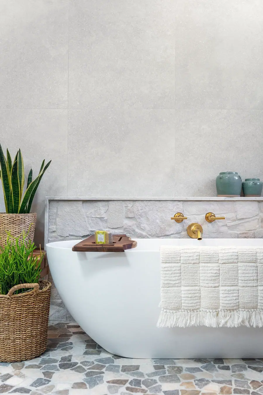 Little Gem soaking tub detail with wood bath tray, woven towel, and brass wall faucet