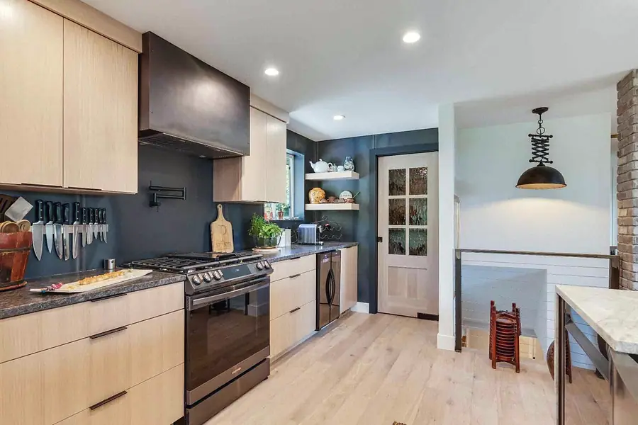 Wallace Project kitchen with light wood cabinetry, dark backsplash, and range