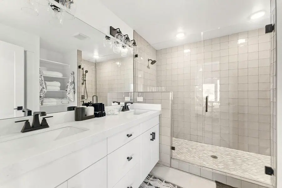 Silver Creek primary bath with double vanity, glass shower, and beige tile