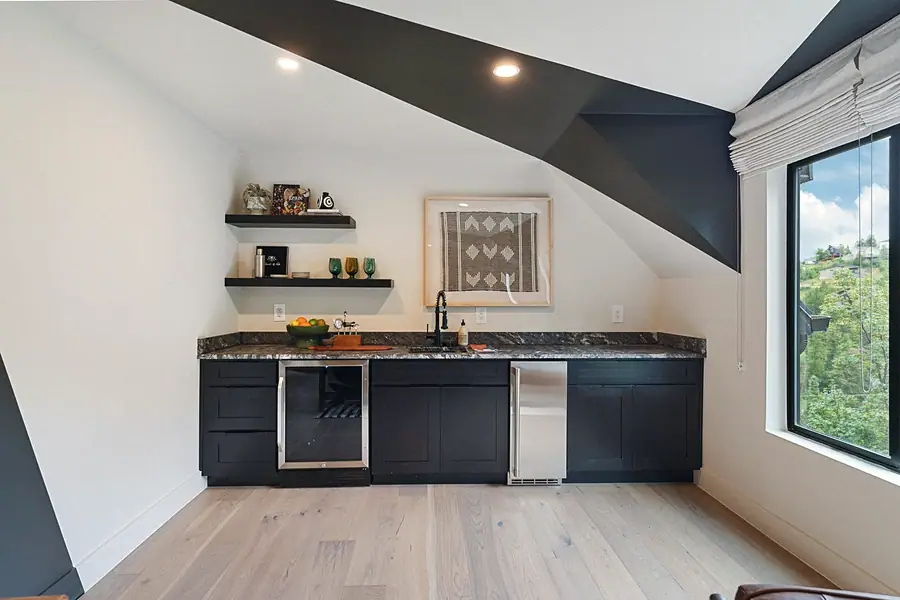 Matterhorn Hygge House wet bar with black cabinetry, stone counters, and mountain window views