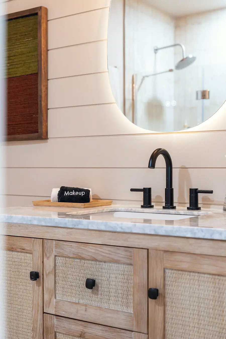 Midway bathroom vanity with round mirror, black fixtures, and light wood cabinetry