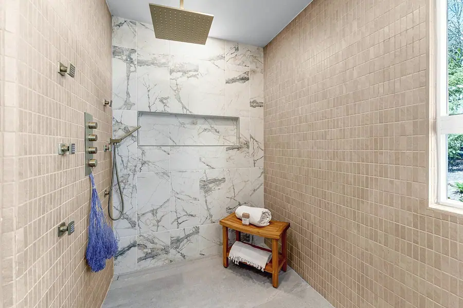 Grand Vista walk-in shower with marble feature wall, rain head, and body sprays