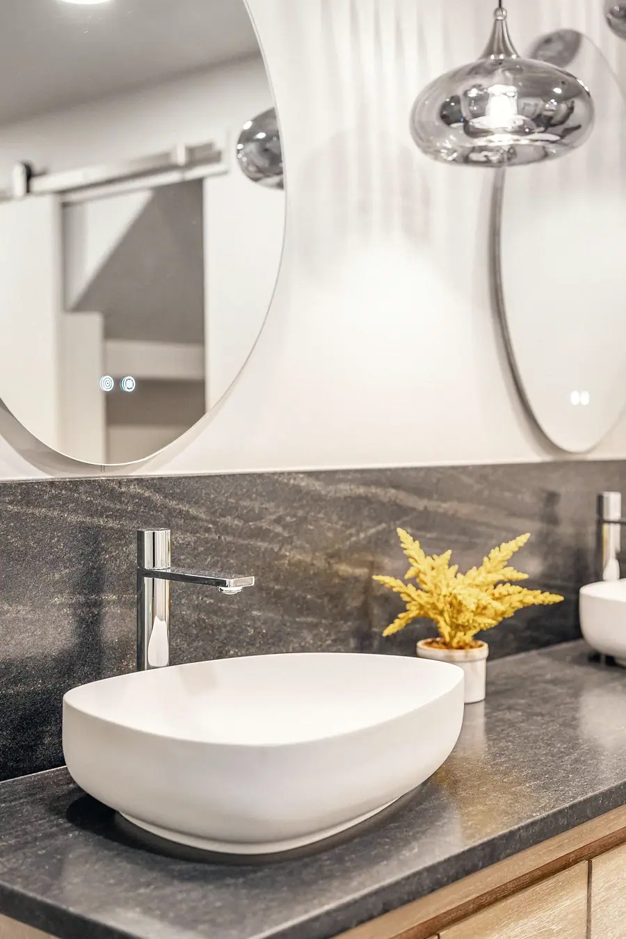 Grand Vista vessel sink detail with chrome faucet, dark stone counter, and yellow dried plant