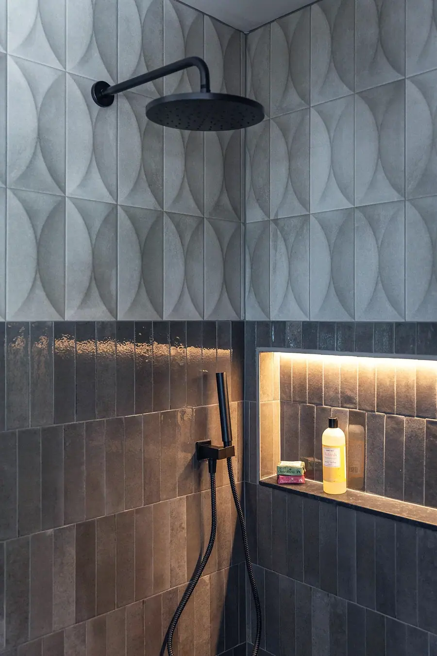 Little Gem shower with geometric tile, black rain head, and lit niche