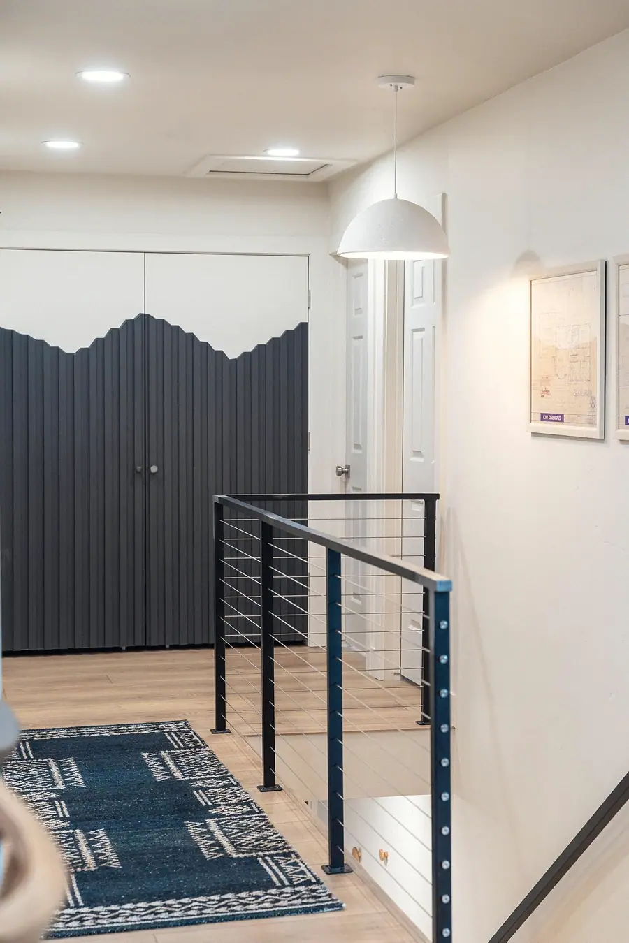 Midway loft landing with dark fluted mountain closet doors, cable rail, and dome pendant