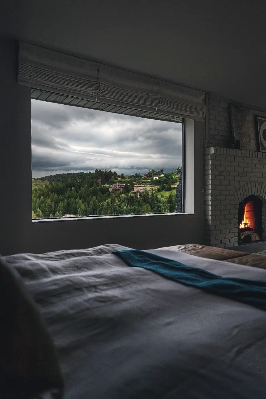 Matterhorn Hygge House bedroom with stormy mountain view window and lit brick fireplace