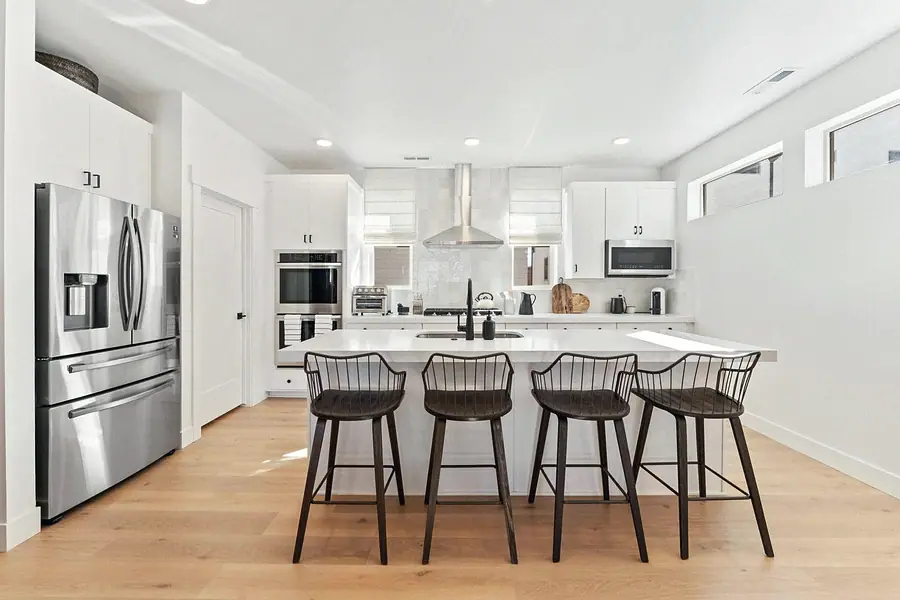 Silver Creek open kitchen with white island, dark wire bar stools, and stainless appliances