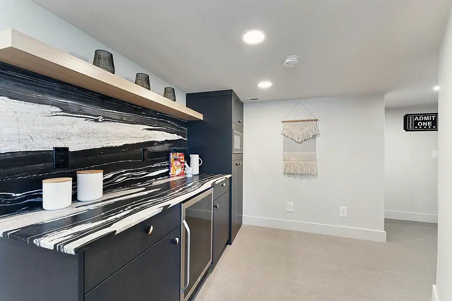 Fairway House basement wet bar with dramatic black-and-white stone counter