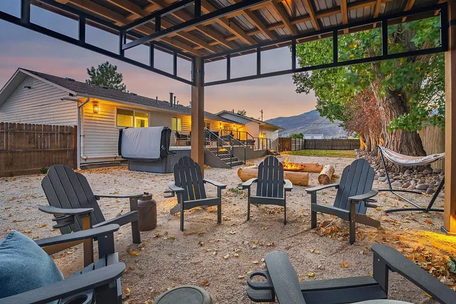 Midway pergola seating with Adirondack chairs looking toward deck, hot tub, and sunset mountains