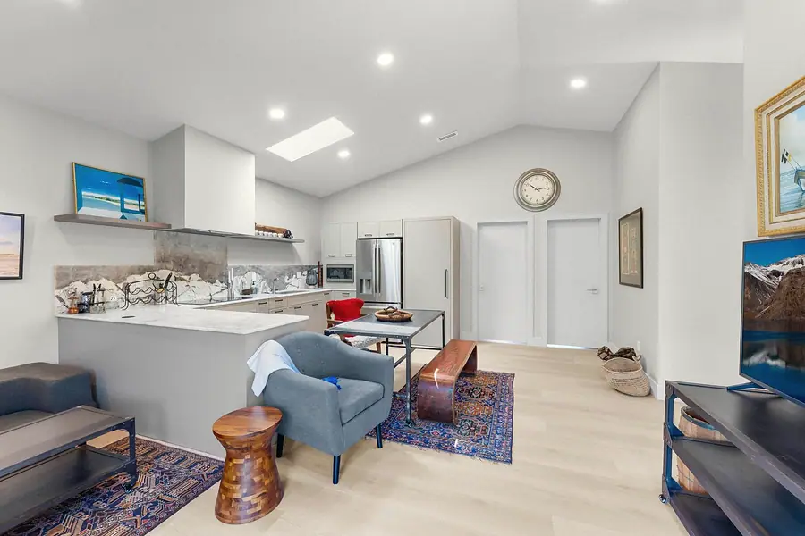 Elysium open kitchen and living with marble island, gray armchair, and vaulted ceiling